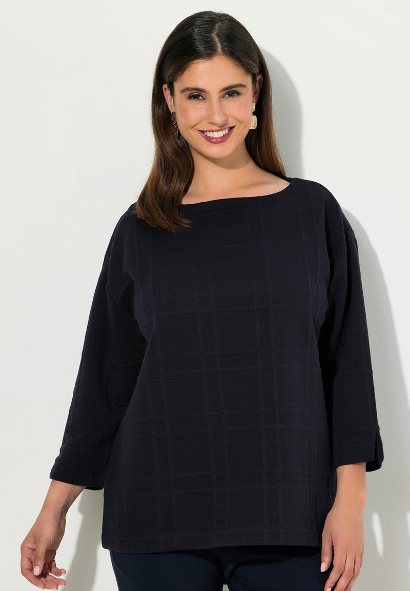 Top blu navy con scollatura quadrata, maniche tre quarti e motivo a griglia testurizzato. Il tessuto sembra morbido con una vestibilità comoda.