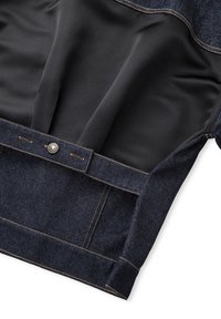 Jeans in denim scuro con una fodera nera liscia, bottone in rame e cuciture in contrasto lungo la vita e le tasche.