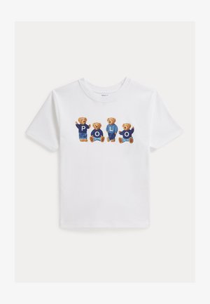 Fehér rövid ujjú póló, amelyen négy, kék ruhát viselő mackó látható, mindegyik mellkasán egy betű, amelyek együtt a "POLO" szót alkotják.