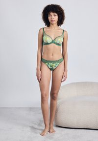 Roheline tikitud pitsist rinnahoidja ja sobivad bikiinid, millel on läbipaistev kangas, lillemustrid ja pehmed servad. Komplekti kuuluvad reguleeritavad rihmad.