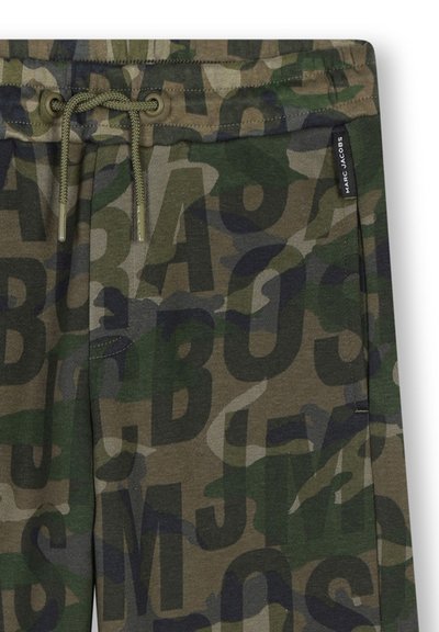Camouflage-print joggers in donkergroen en bruin, met grote zwarte letters. Koordjes tailleband met metalen uiteinden en een zijlabel.