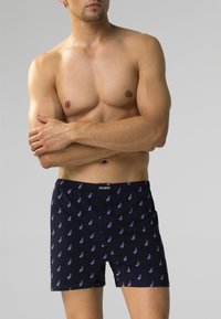 Ciemnoniebieskie bokserki z wzorem małych fioletowych bakłażanów, elastyczny fason w pasie i dwa guziki z przodu. Miękka tekstura materiału.