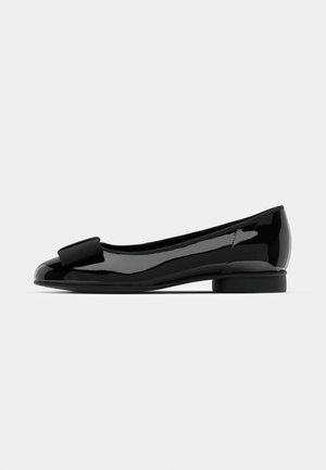 Ballet plat en vernis noir avec un bout arrondi, mettant en avant un accent nœud à l'avant et un talon bas et rond. Surface lisse et brillante.