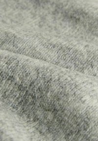 Harmaa kangas, jossa on teksturoitu, kudottu kuvio, joka esittelee hienovaraisia sävyvaihteluita ja pehmeää, pörröistä pintaa. Sopii vaatteisiin tai verhoiluun.