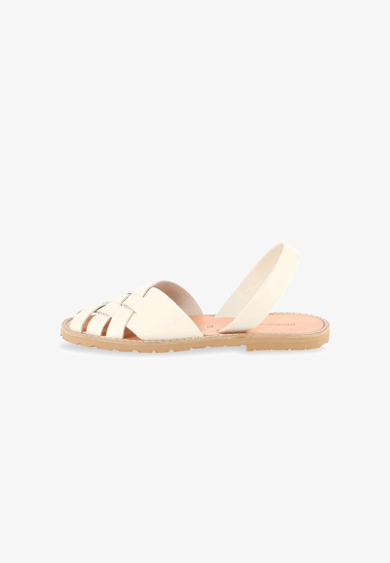 Sandale plate avec des lanières en cuir tressé blanc, une semelle intérieure couleur tan et une semelle extérieure en caoutchouc beige, avec un bout ouvert et une bride arrière pour un maintien sécurisé.