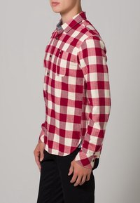 Rode en witte geblokte flanellen shirt met een kraag, knoopsluiting aan de voorkant, een zak aan de linkerkant en zwarte knopen. Regular fit en lange mouwen.