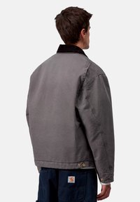 Gray cotton jacket with a corduroy collar, relaxed fit, and golden hardware accents. Features a clean, minimalist design.