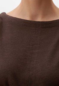 Donkerbruin kledingstuk met een brede halslijn, met een zachte, gladde textuur en subtiele stiksels langs de randen.