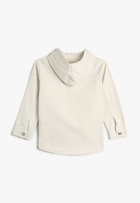 Giacca cappuccio beige chiaro con maniche lunghe, realizzata in tessuto morbido. Presenta un orlo arrotondato e polsini con bottoni. Design semplice, senza motivi.