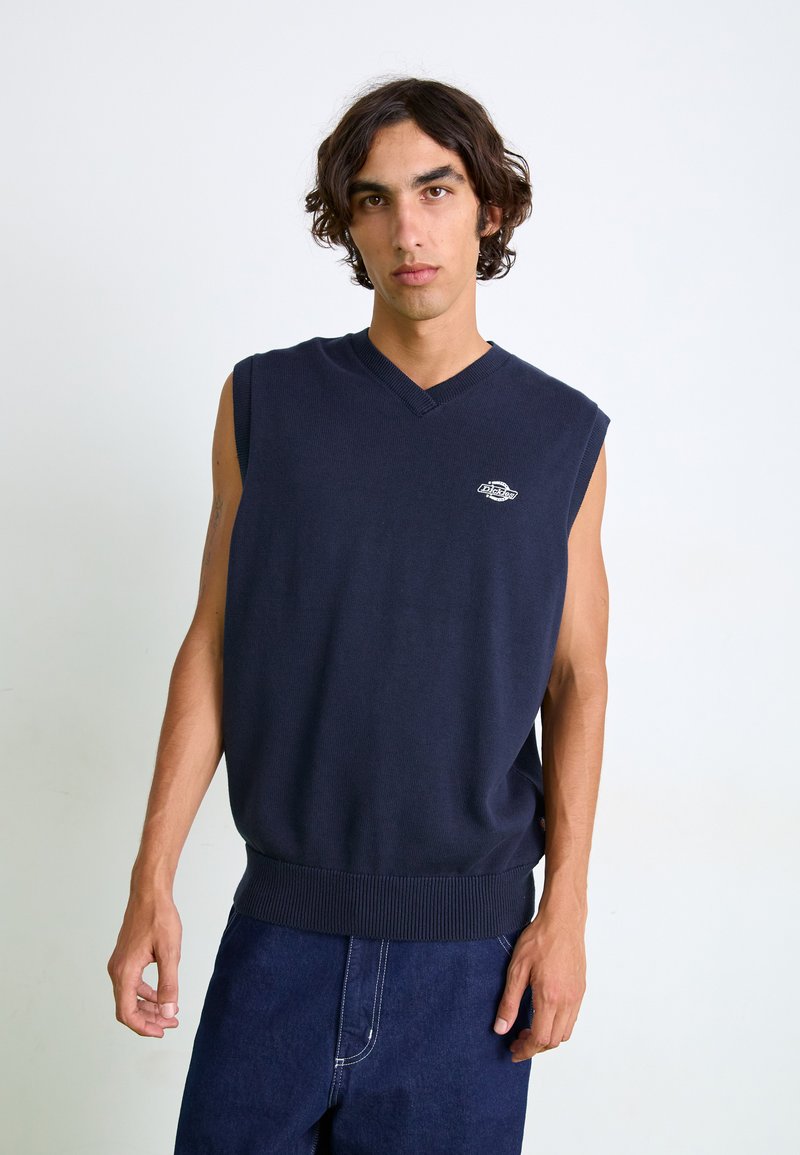 Jersey sin mangas de color azul marino con un escote en V, dobladillo acanalado y un pequeño logo en el lado izquierdo del pecho, hecho de un suave tejido de punto.