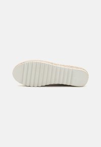 Suela de zapatilla ligera con parte superior texturizada en beige, que presenta una suela de goma blanca estriada para tracción y estabilidad.