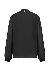 Blouse noire à manches longues avec un col haut, des accents smockés aux manches et une fermeture dos avec ouverture en forme de goutte. Tissu lisse avec une finition semi-transparente.