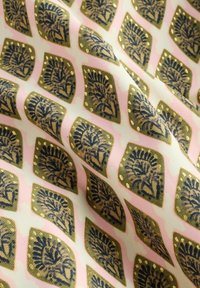 Tela con un patrón que presenta un diseño repetitivo de hojas acentuadas en dorado sobre un fondo rosa claro, con una textura suave y un caído blando.