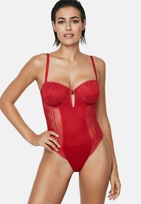 Rode kanten body met doorschijnende zijpanelen, beugelloze cups, geborduurde details en een centrale sleutelgatopening. Inclusief verstelbare bandjes.