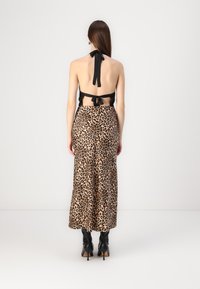 Maxikjørt med leopardmønster og sidesliss, aksentuert med en svart halterneck-top med bånd i nakken og ryggen, parret med svarte høye støvler.