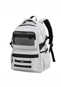 Zaino bianco con accenti neri, numerose tasche con cerniera, spallacci imbottiti, tessuto testurizzato e dettaglio del logo sul davanti.
