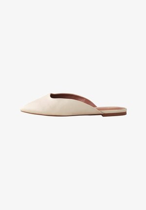 Špičaté slip-on boty z měkké béžové kůže, s otevřeným designem vrchní části a plochou hnědou podrážkou. Minimalistický styl, hladká textura.