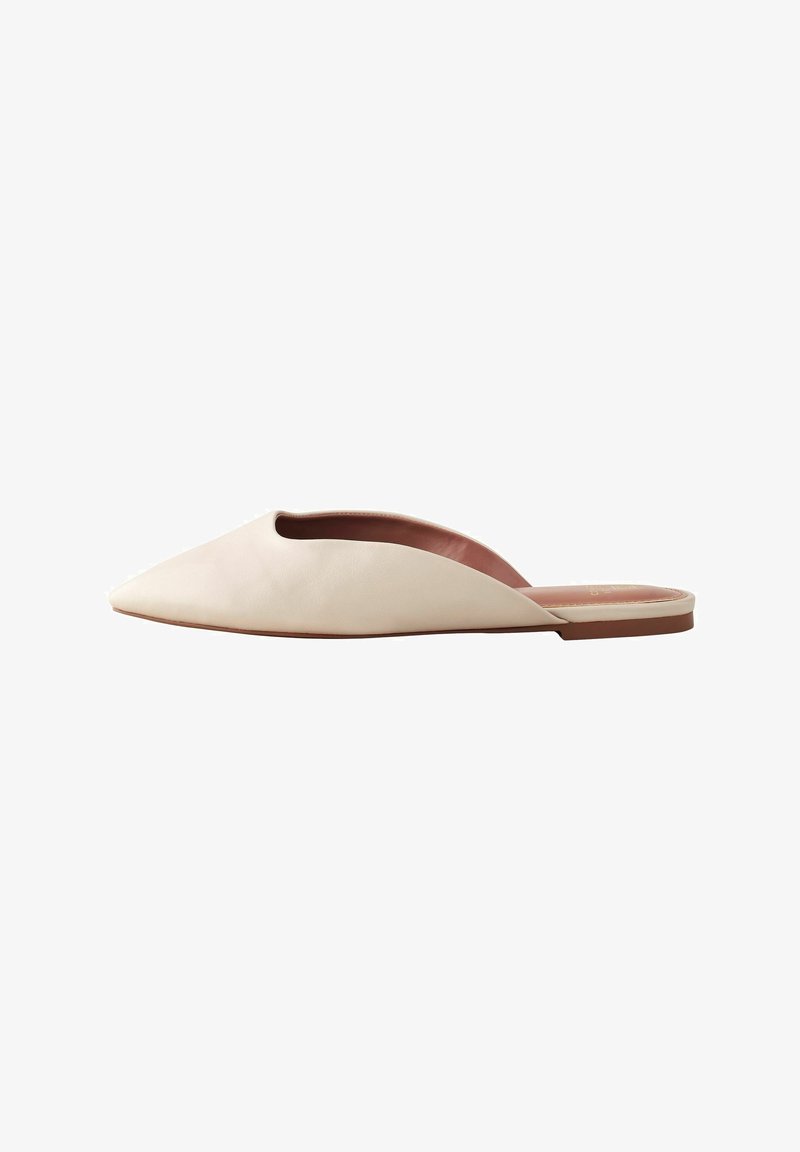 Špičaté slip-on boty z měkké béžové kůže, s otevřeným designem vrchní části a plochou hnědou podrážkou. Minimalistický styl, hladká textura.