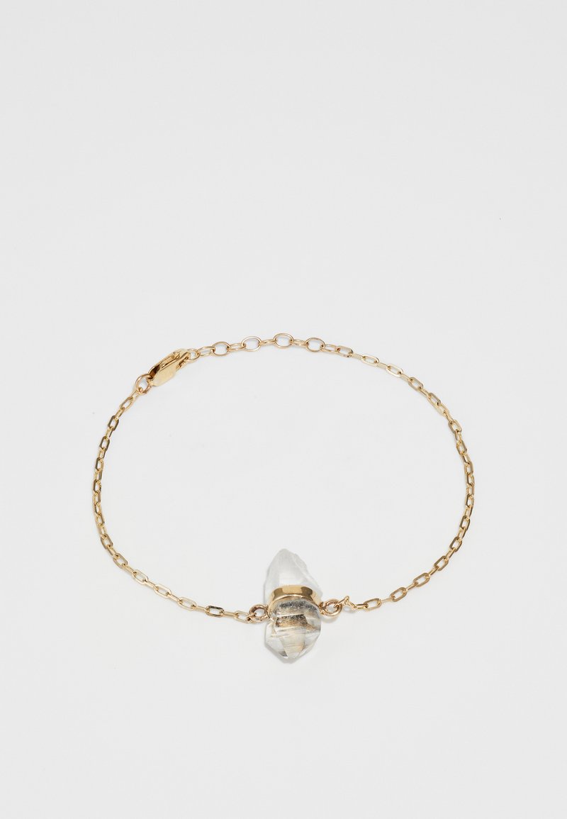 Kuldne käevõru, millel on selge, ebaregulaarses vormis kristallripats, kinnitatud kuldse riba abil, neutraalse tausta vastu.