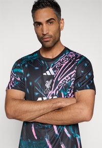 Sort atletisk t-shirt med korte ærmer og farverigt abstrakt print i pink og blågrøn, med Adidas-logo og Liverpool FC-emblem på brystet.