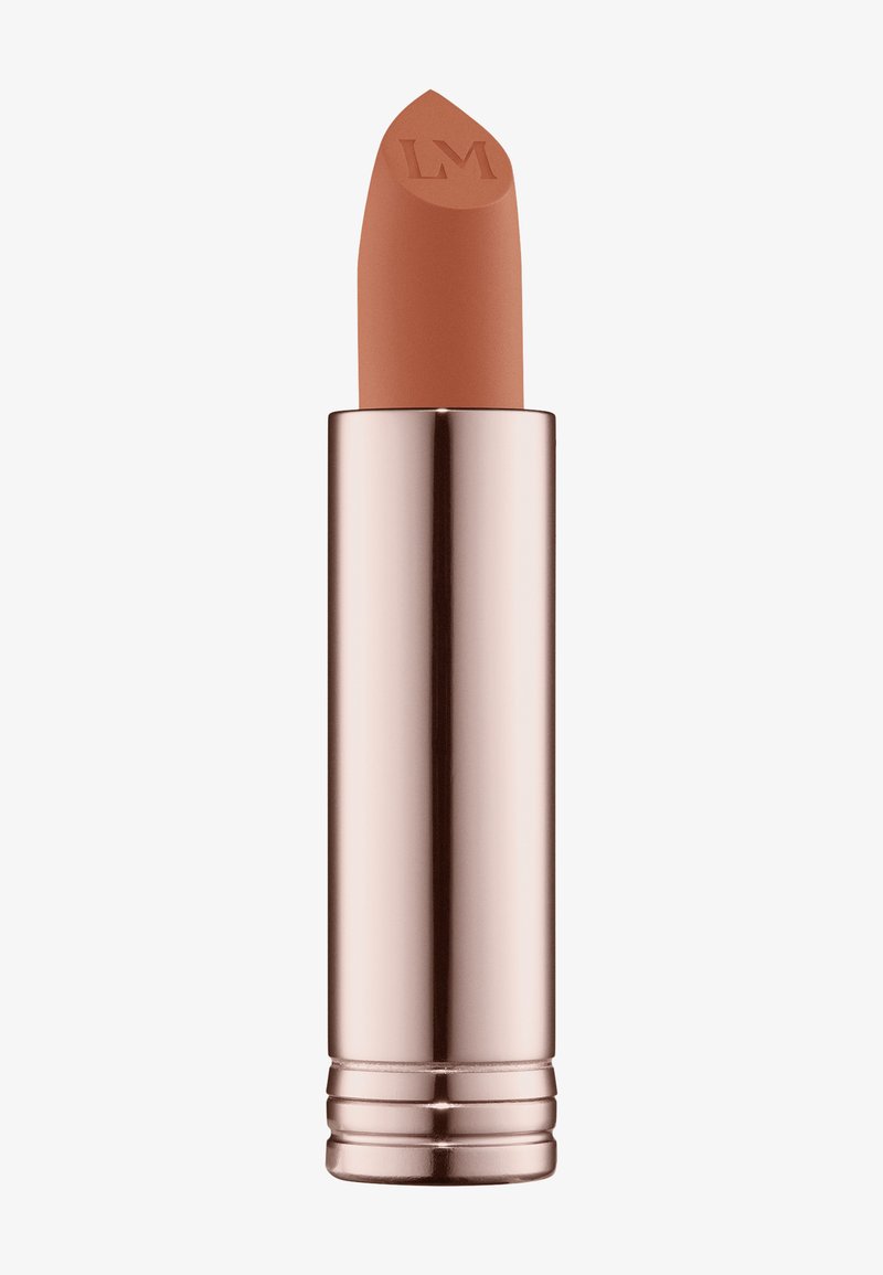 Matt leppestift i nøytral beige med skrå spiss, plassert i et reflekterende rosagullrør med inngravert logo og ribbet bunn.