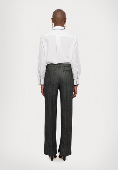 White shirt with puffed sleeves and contrasting stitching, paired with high-waisted, wide-leg gray pinstriped trousers.