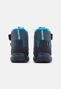Zapatos infantiles en azul marino y verde azulado, con parte superior de tejido texturizado, correas ajustables de velcro y suela de goma. Parte trasera reforzada con acentos reflectantes.