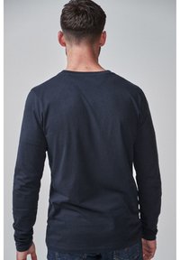 Pikaevarvane sinine särk, ümarate kaelustega, valminud pehmest puuvillast. Omab sileda tekstuuri ja lihtsat, minimalistlikku disaini.