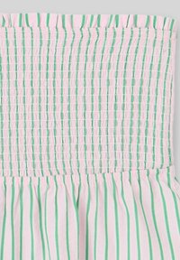 Vêtement sans bretelles avec un bustier smocké arborant des rayures verticales roses et vertes. Tissu doux et léger avec un bas évasé.