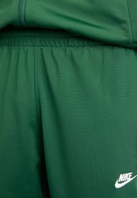 Shorts de sport Nike verts, fabriqués avec un tissu doux et texturé, dotés d'une taille élastique et d'un petit logo blanc près de l'ourlet.