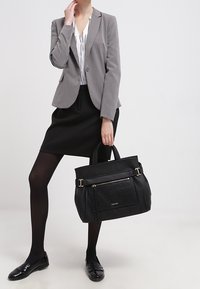 Black textured tote bag with two handles, a front zip pocket, and gold-tone hardware. Features a structured shape ideal for professional settings.