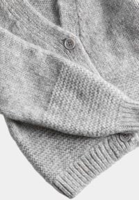 Lichtgrijze gebreide cardigan met getextureerde breipatronen, geribde manchetten en zoom, en twee zichtbare knopen met vier gaten.