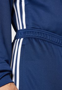 Navy athletic fabric featuring a textured finish, with white horizontal stripes and an elastic waistband, displaying sporty design elements.
