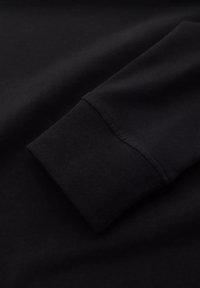 Černá dlouhá rukávová tkanina s hladkým povrchem; obsahuje žebrované manžety; minimalistický design; žádné vzory ani detaily viditelné.