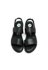 Sandalias negras con dos correas anchas en la parte delantera y una correa en el tobillo. Hechas de material suave, con un logotipo redondo en el interior.