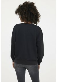 Sweatshirt noir oversize avec un col rond, des épaules tombantes et des poignets côtelés. Design minimaliste, texture douce.