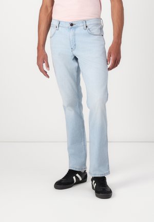 Jean en denim bleu clair avec une coupe droite, présentant un design classique à cinq poches, des coutures marron et un bouton en métal de fermeture.