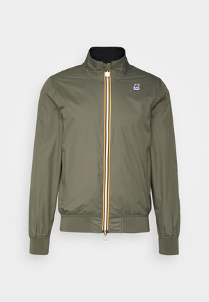 Chaqueta ligera color verde oliva con cierre de cremallera, puños y dobladillo acanalados, detalle de cremallera a rayas y pequeño logo en el pecho izquierdo.