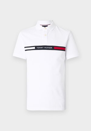 Polo blanc en coton avec une patte de boutonnage à trois boutons, doté d'une bande horizontale noire et rouge avec le texte "TOMMY HILFIGER".