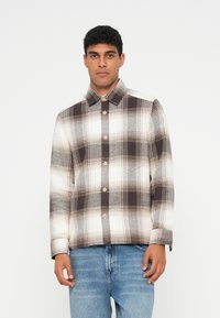 Rutet skjorte i beige og brune nyanser, med knappestolpe foran, krage og lange ermer med en teksturert, rutete mønster.