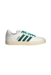 Zapatilla baja blanca de Adidas con franjas y cordones verdes, suela beige y lengüeta de ante en la parte trasera, sobre fondo blanco.