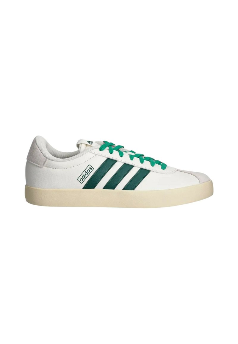 Zapatilla baja blanca de Adidas con franjas y cordones verdes, suela beige y lengüeta de ante en la parte trasera, sobre fondo blanco.