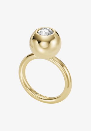 Ring i guldtonat metall med en slät, rundad band och en stor, klar sten fäst i en sfärisk bezel. Graverad logotyp på den inre bandet.