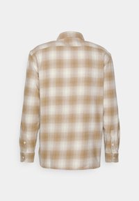 Camicia a maniche lunghe plaid in tonalità nocciola e crema con polsini abbottonati e colletto aperto. Tessuto morbido con una finitura leggermente texture.
