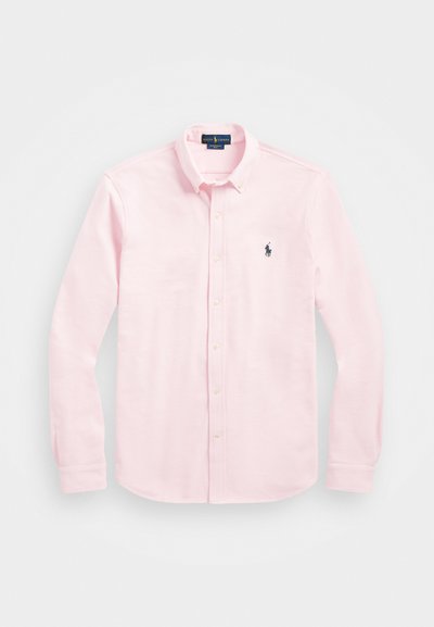 Hosszú ujjú, világos rózsaszín pamut ing, galléros nyakkal, bal mellen egy kis sötétkék logóval és gyöngy színű gombokkal.