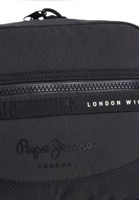 Čierny batoh s textúrovaným povrchom, ktorý má výrazné zapínanie na zips, tkané akcenty a embosované logo Pepe Jeans, London.