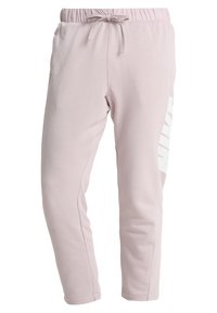 Ljusrosa träningsoverallbyxor med elastisk midja, justerbar dragsko och stor vit "NIKE"-logotyp på sidan. Mjukt tyg med smalnande ben.