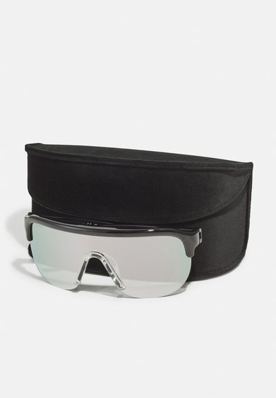 Black sports sunglasses with transparent lenses, featuring a wraparound design. Accompanied by a black velvet case.