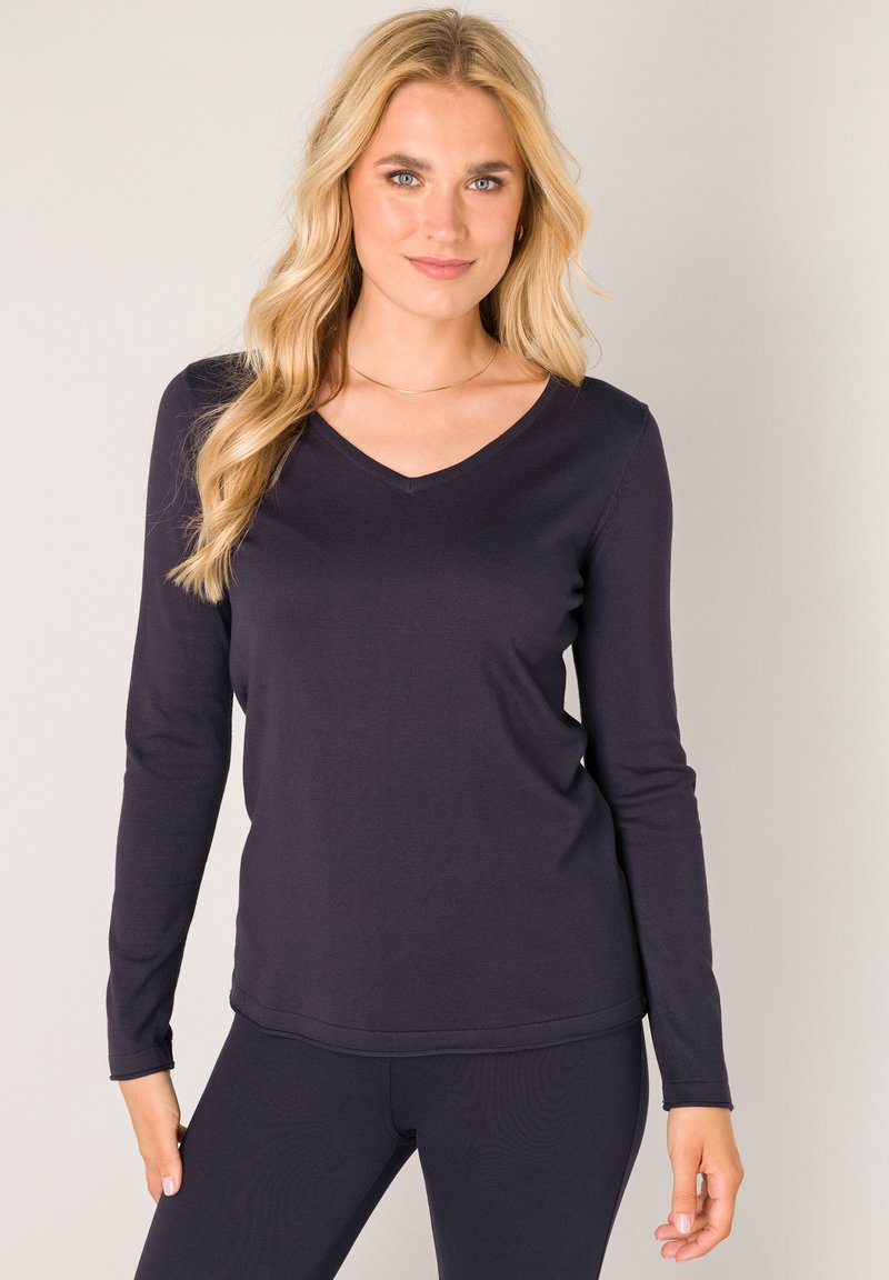 Marineblauwe longsleeve top met V-hals, geribbelde textuur en getailleerde pasvorm, gecombineerd met bijpassende donkere legging. Soepele stof, eenvoudig ontwerp.