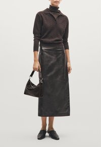 Maglione a collo alto in maglia cable-knit marrone scuro, gonna in pelle a vita alta, borsa rigida scura e mule neri flat. Texture lisce e linee pulite.